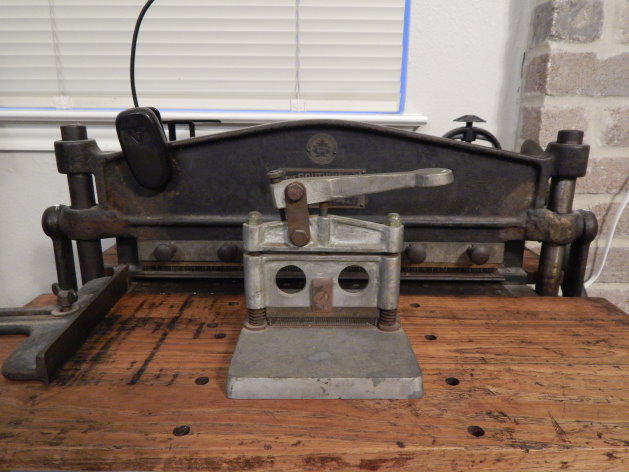 Miniature perforating machine sitting on top of Southworth tabletop perforator