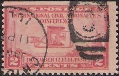 Red 2-cent U.S. postage stamp picturing biplane in flight near Washington Monument and U.S. Capitol